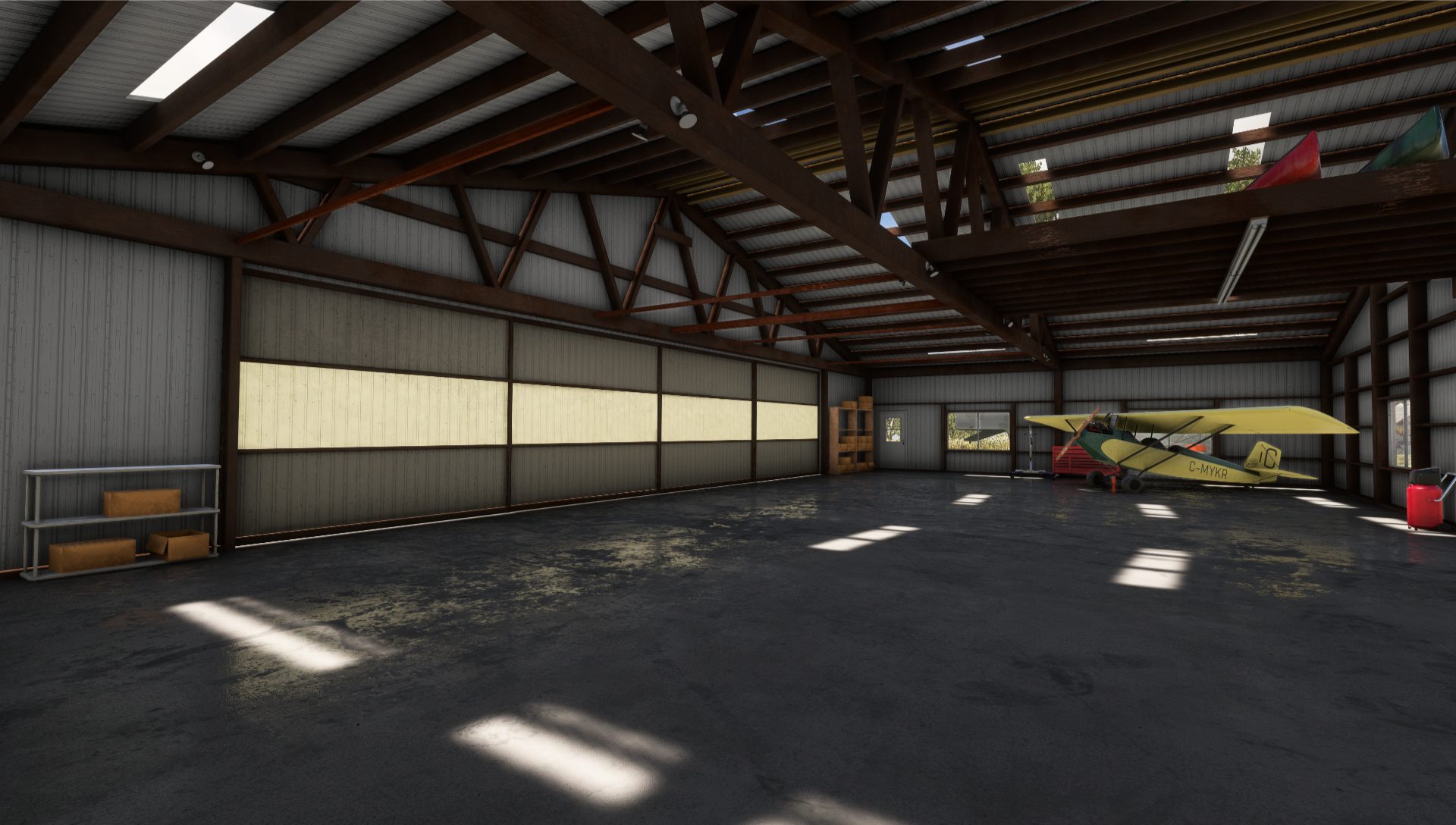 Inside of a closed hangar with a Pietenpol in the corner and light illuminating the hangar door panels